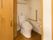 居室のトイレである。壁にはL字型の手すりと温水洗浄便座の操作パネル、トイレットペーパーホルダーがついている。