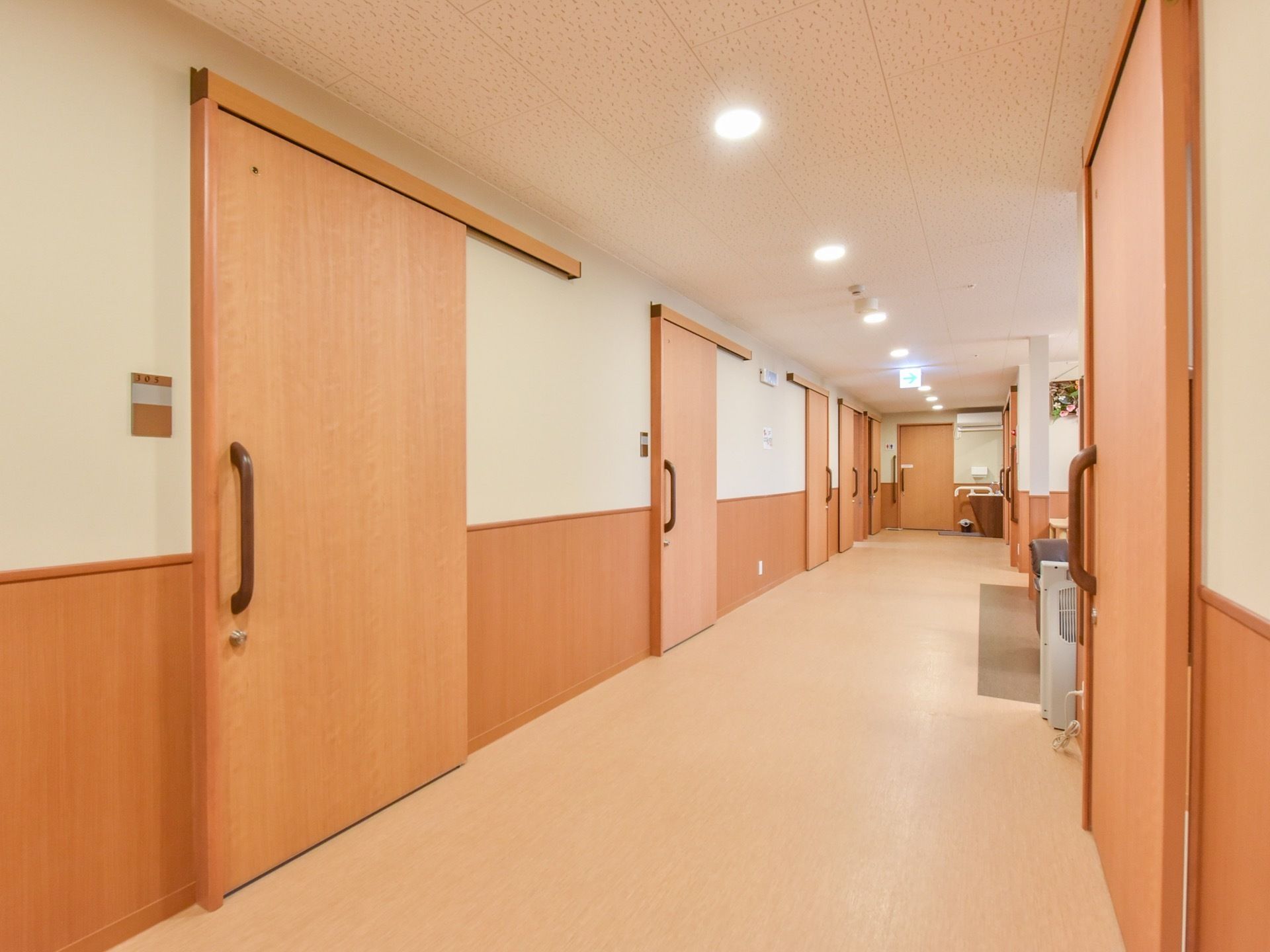 照明が明るい廊下は白を基調としている。通路の幅に十分なスペースがあるので歩行器などご利用する入居者様も安心して通行できる。