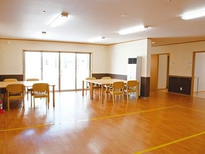 掃出し窓があり、日当たりも良好で明るい。床面はフローリングで段差がない。木製のテーブルセットが設置されている。