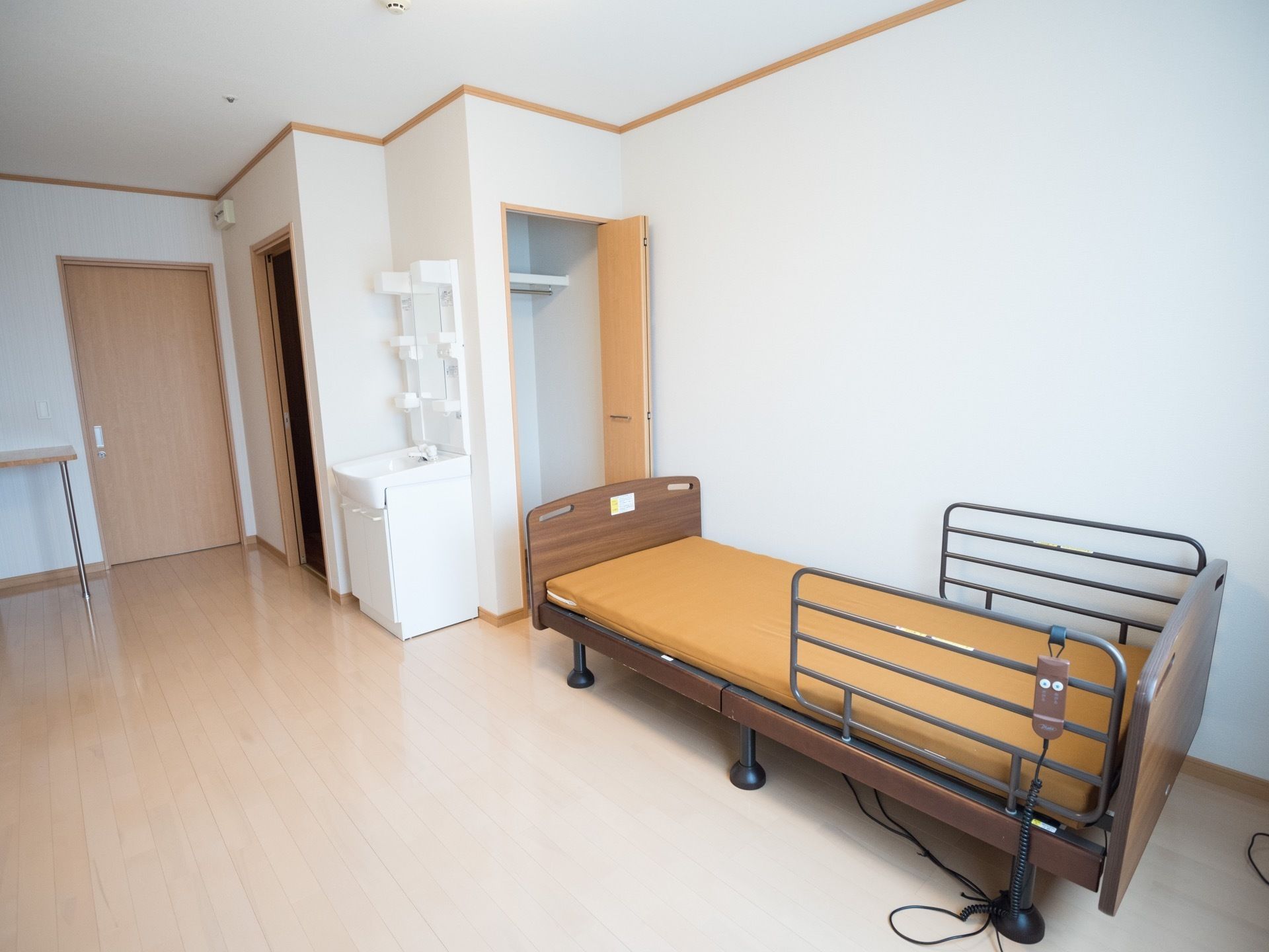 クローゼットや洗面台が備え付けられている居室で、床はフローリングとなっている。壁沿いには、リクライニングベッドが置かれている。