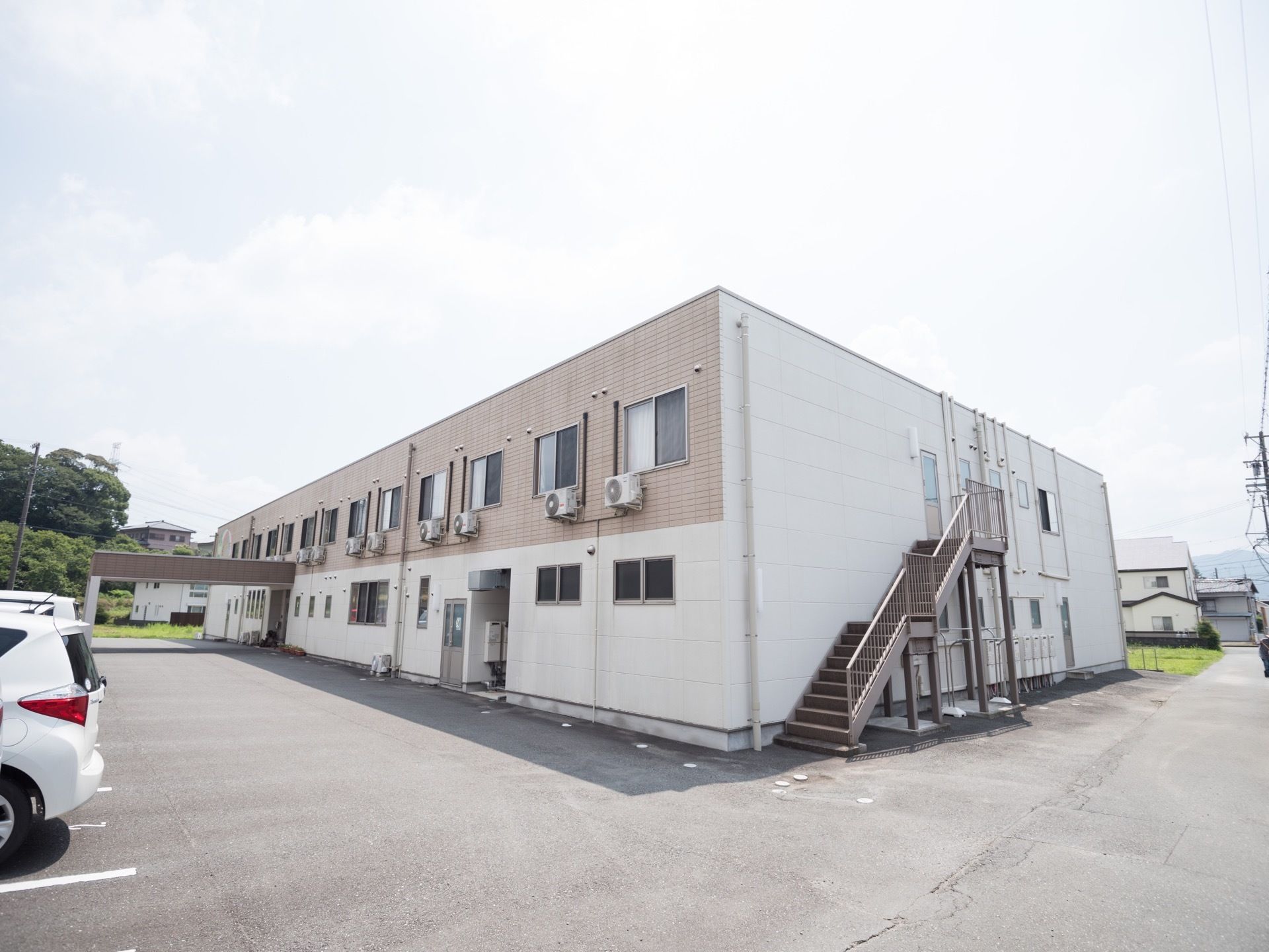 ２階建ての大規模な建物である。非常階段が設置されている。周辺はアスファルトで舗装され駐車スペースが広がっている。