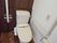 ダークブラウンの木目と白い壁とのコントラストがおしゃれなトイレである。ナースコールや手すり、温水洗浄便座が完備されている。