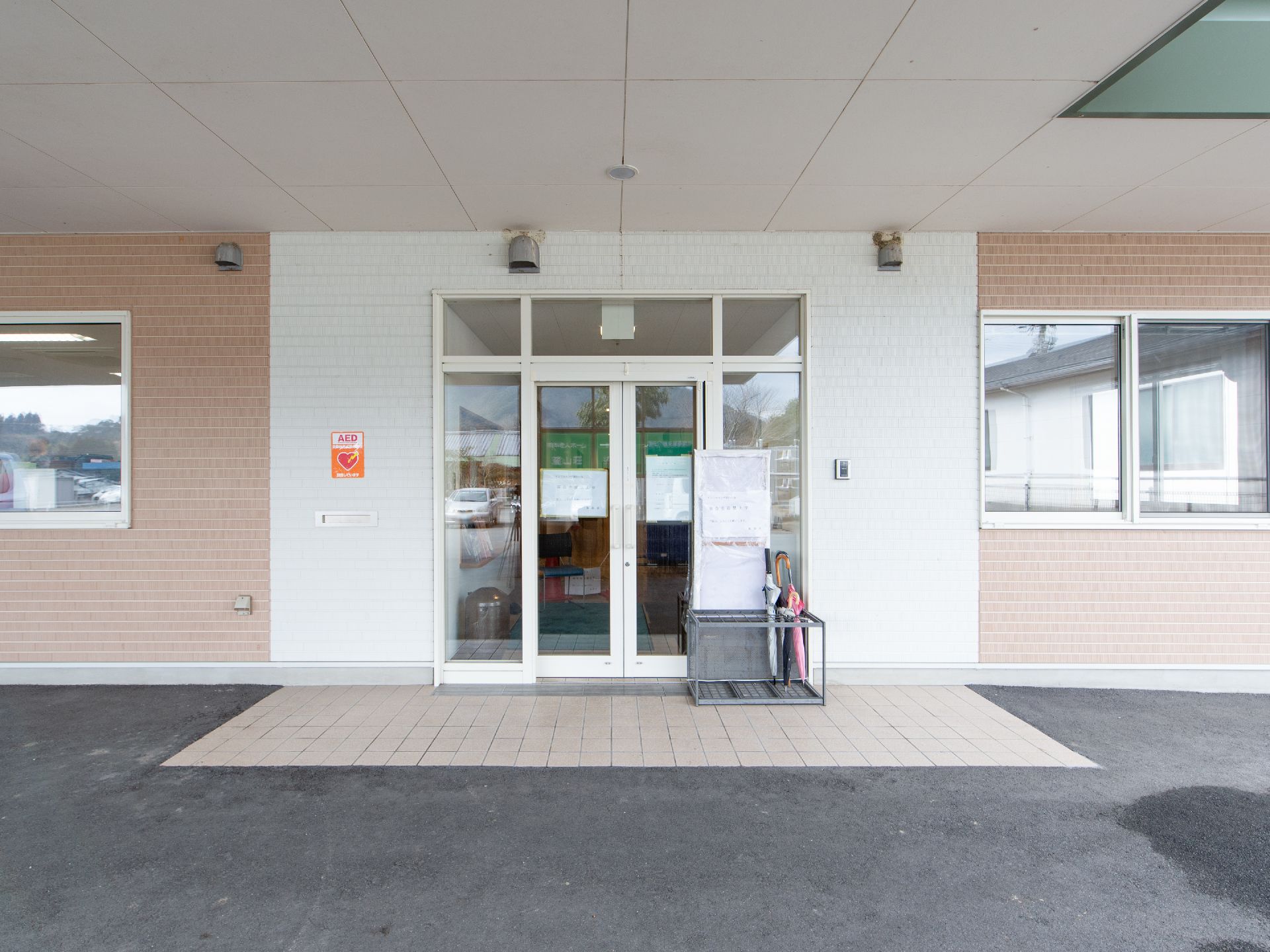 玄関は車寄せの構造になっている。玄関前には傘立てがあり、傘が数本ある。AED設置の表示が玄関扉の左側に掲示されている。