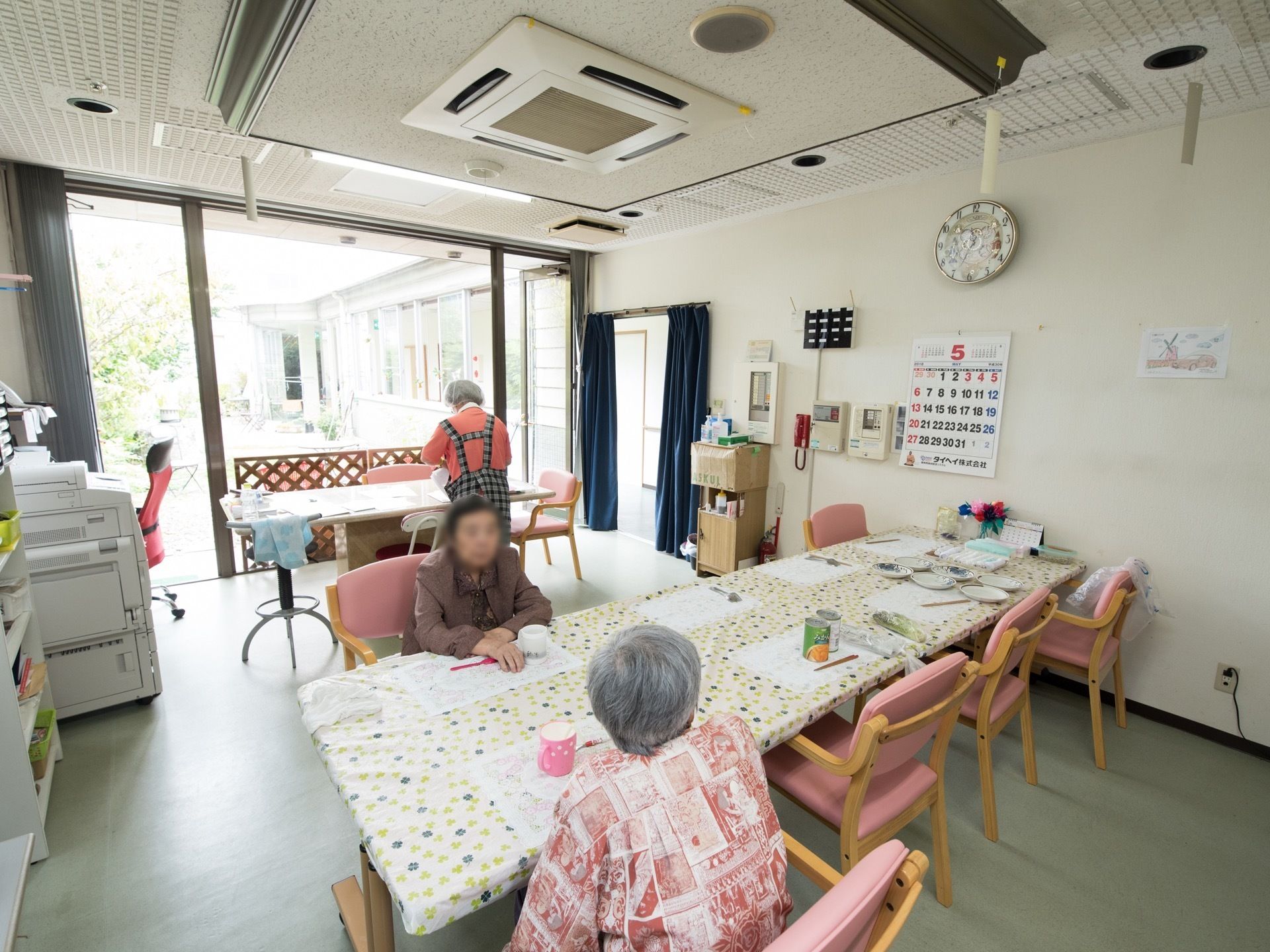 食堂にはテーブルクロスがかけられたテーブルが3つ置かれている。1つのテーブルには2人の入居者様が座っている。