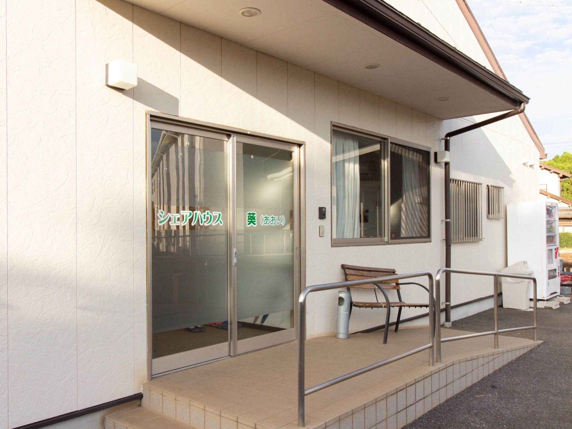施設名が入ったドアが玄関である。玄関前はスロープになっていて、手すりが設置されているほか、ベンチがあり、休憩スペースにもなっている。