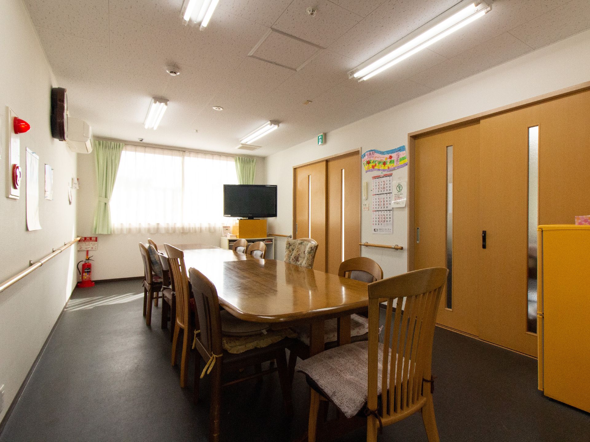 部屋の中央に細長い木製のテーブルと複数の椅子が設置されたリビング