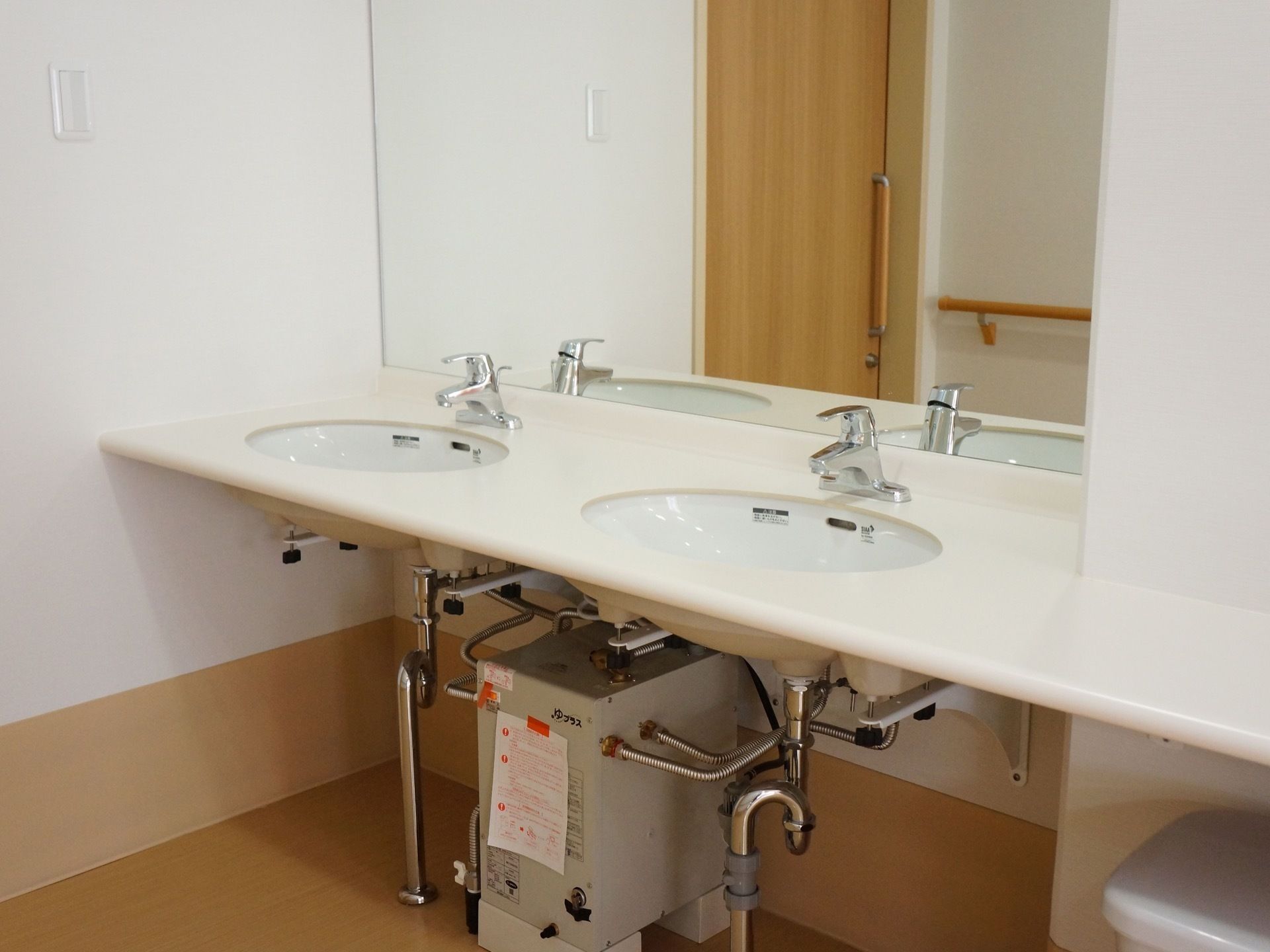 白色を基調とした洗面台には洗面ボウルが2つ備わり、全面の壁には大きな鏡が取り付けられている。蛇口はレバー式である。