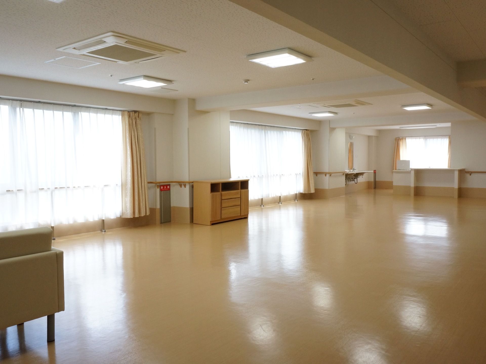 淡い茶色のフローリングの広い室内には大きな窓があり開放的である。室内の一角には洗面台があり、ソファーが置かれているスペースもある。