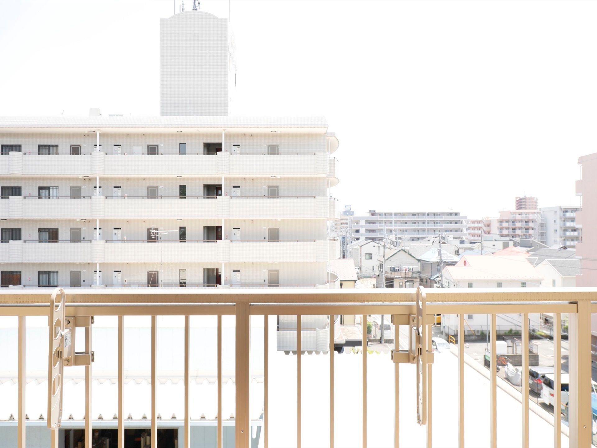 マンションが見える。ベランダには転落防止の柵が備え付けられている。物干し竿受けが取り付けられていて、洗濯物を外に干すことができる。
