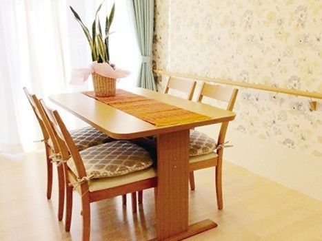 木製の４人掛けのテーブルと椅子が置かれた手すりのある花柄の壁の部屋