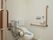 明るい床、白い壁でデザインされたトイレである。可動式の手すりも備え付けられており、入居者様の動作をサポートしている。