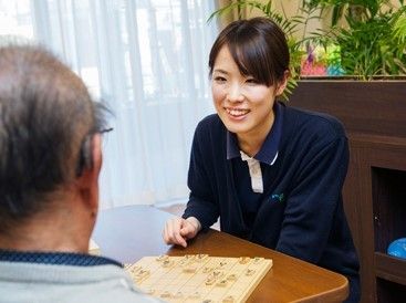 窓の近くで楽しそうに将棋を打っている高齢の男性と若い女性