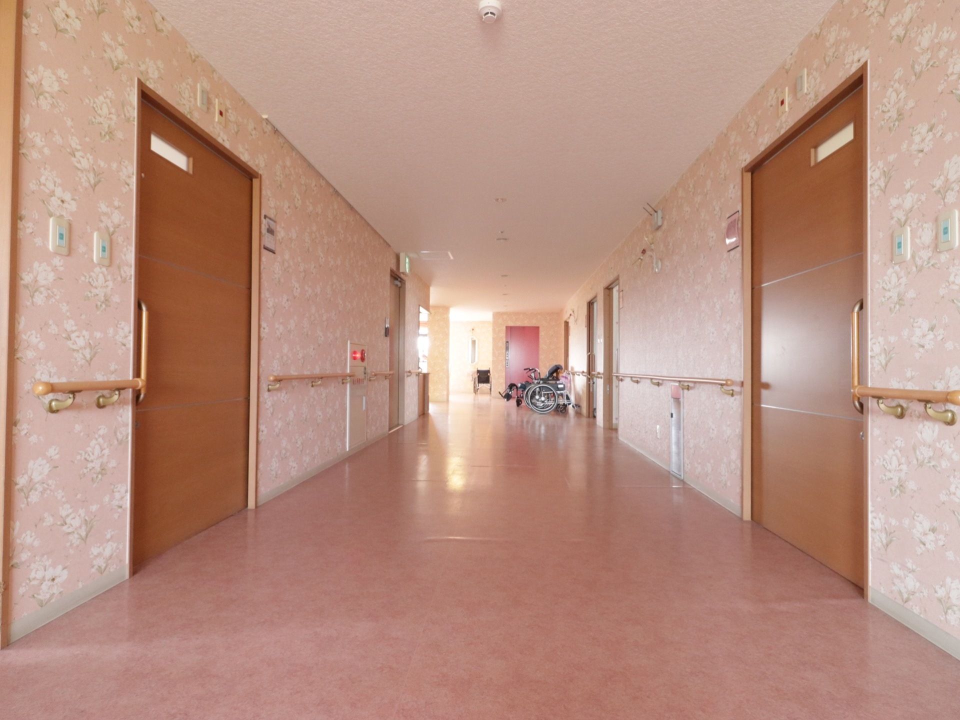 幅広くスペースが確保された居室前の廊下である。壁は華やかなデザインとなっており、手すりが設置されている。