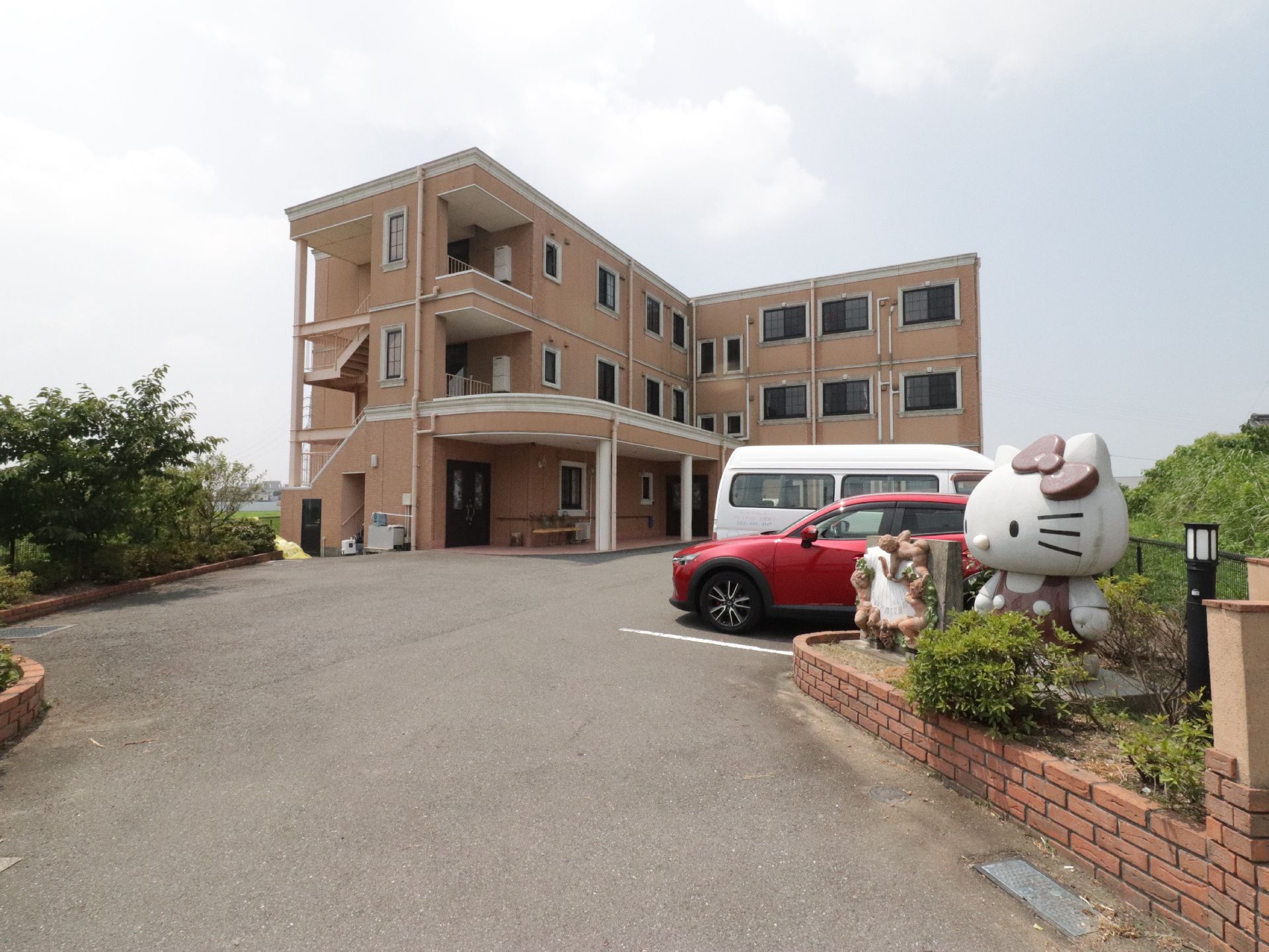 入口付近に人気キャラクターが置かれた駐車場とオレンジ色の建物