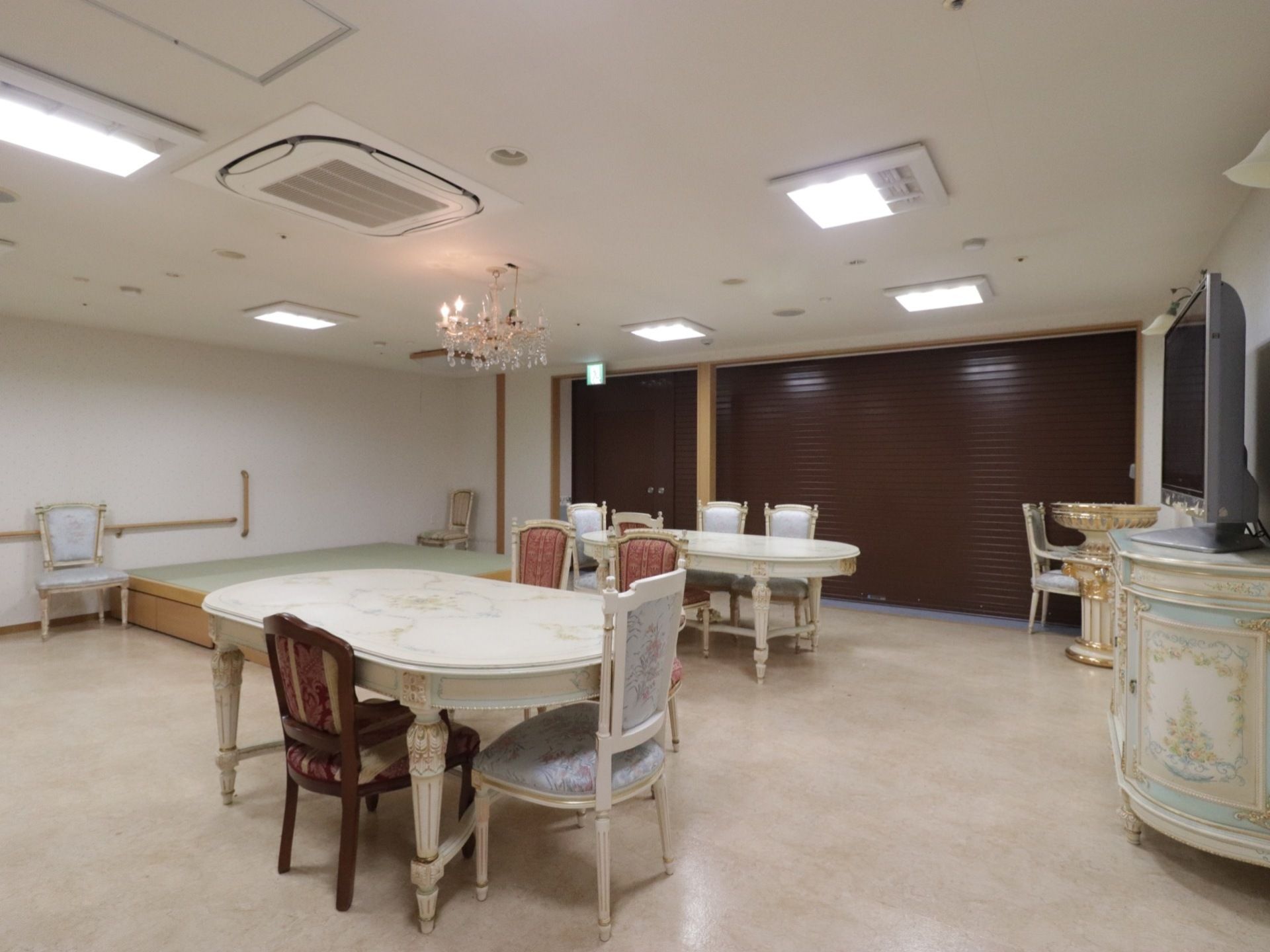 ２台のダイニングテーブルが置いてあり、テーブルの周りに数脚の椅子が配置されている。壁際にテレビが設置されている。