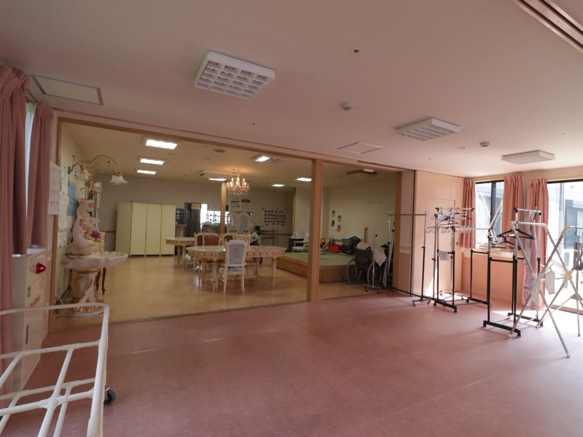 ２つの部屋に間仕切りがなく、広いスペースになっている。窓際に数台の物干し台が置いてあり、ハンガーが掛けられている。