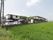 広い田んぼの中に２階建ての建物が建っている。アスファルトで整備された駐車場に数台の車が停められている。