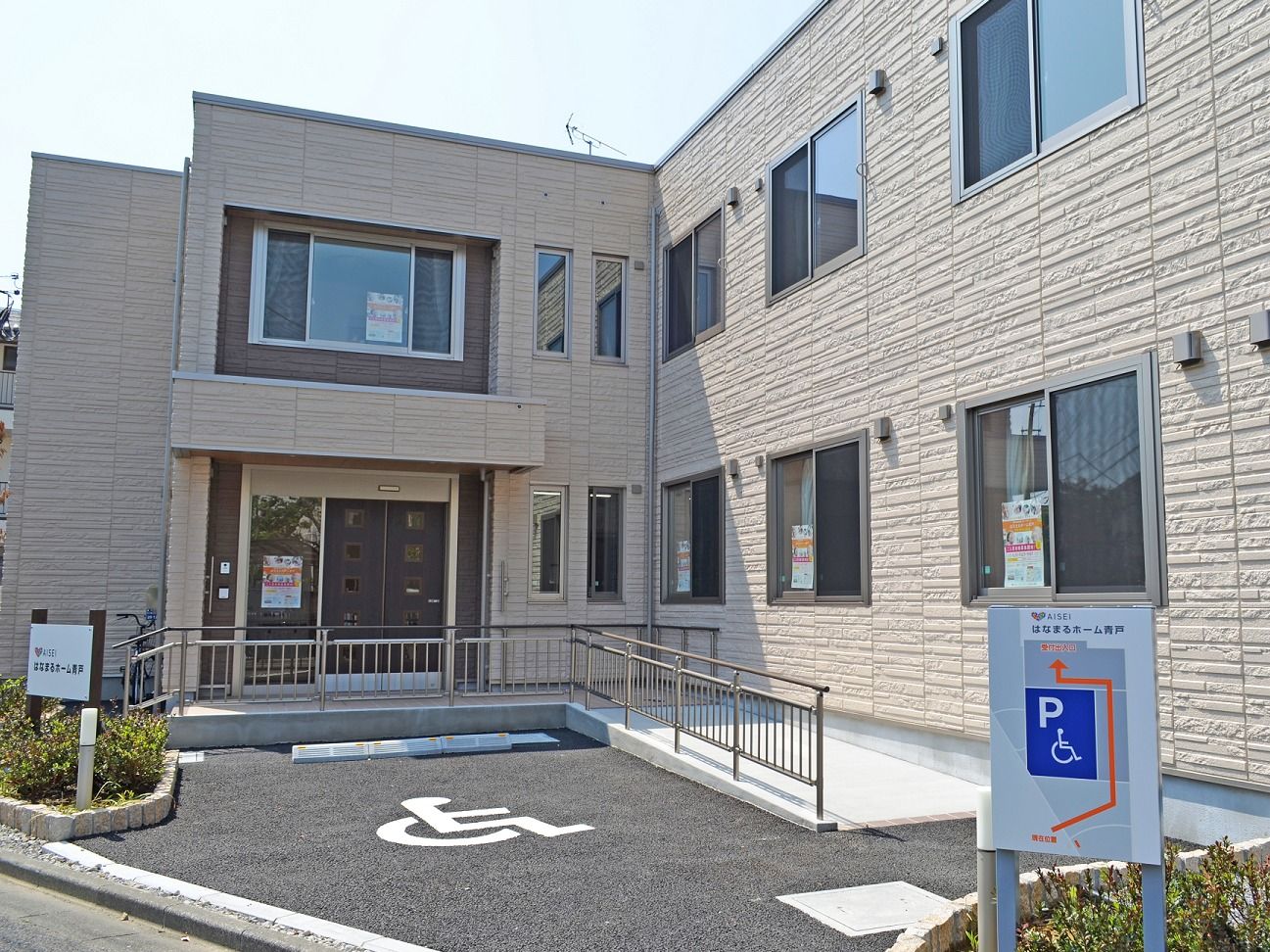 施設までは階段とスロープが設けられている。入居者様が身体の状態に合わせて入場できる。居室の窓に印刷物が数枚貼られている。