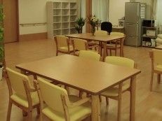 レンジや冷蔵庫が備え付けられている開放的なリビングである。テーブルや椅子が複数セッティングされている。