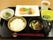 お盆の上に食事が並べられている。ご飯、お味噌汁、そして焼き魚といった和食である。手前にはお箸が置かれている。