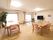 観葉植物が部屋の隅に置いてあり、壁には花束が飾られている。テレビの近くには、カレンダーが貼ってある。