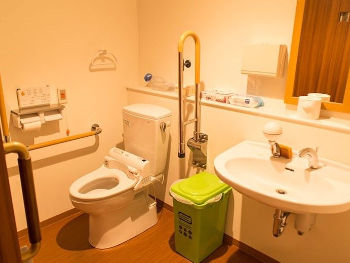 手すりがついたトイレ。温水洗浄機を取り付けている。トイレ近くにゴミ箱を設置しているため、いつでも清潔に利用することができる。