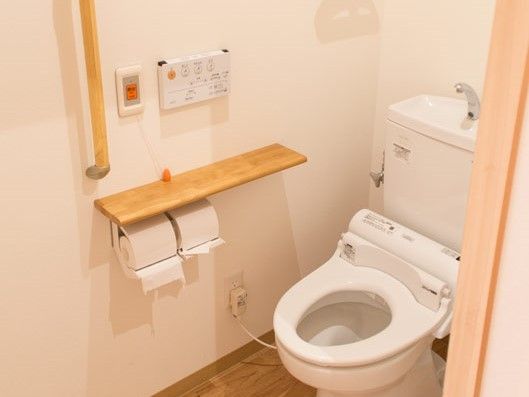 手すりのついたトイレ。温水洗浄便座を採用している。緊急時には、スタッフを呼び出せるボタンも設置している。