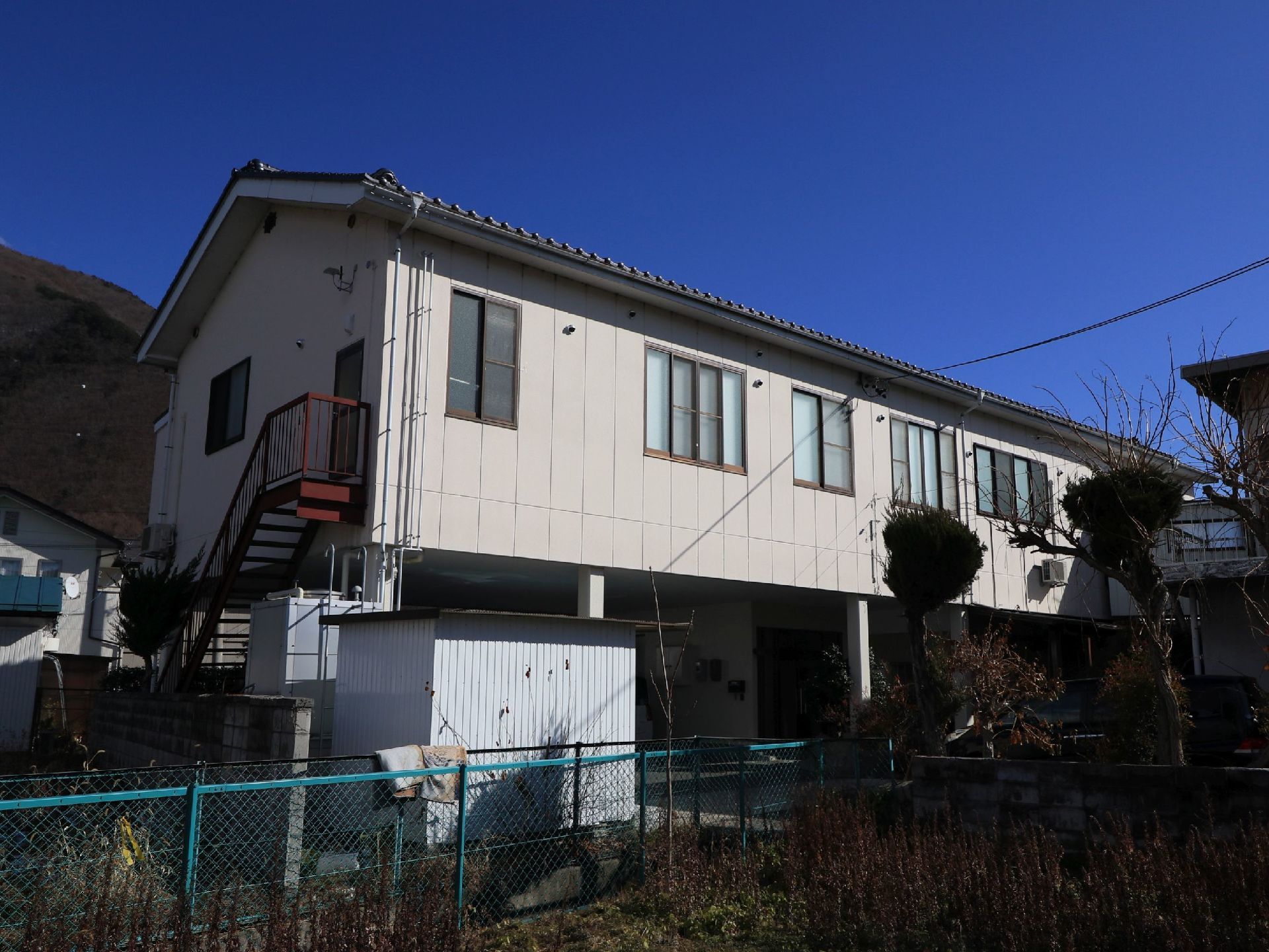 薄いベージュ色が基調の２階建ての建物である。外階段が設置されており、緊急時も直接２階から非難することができる。