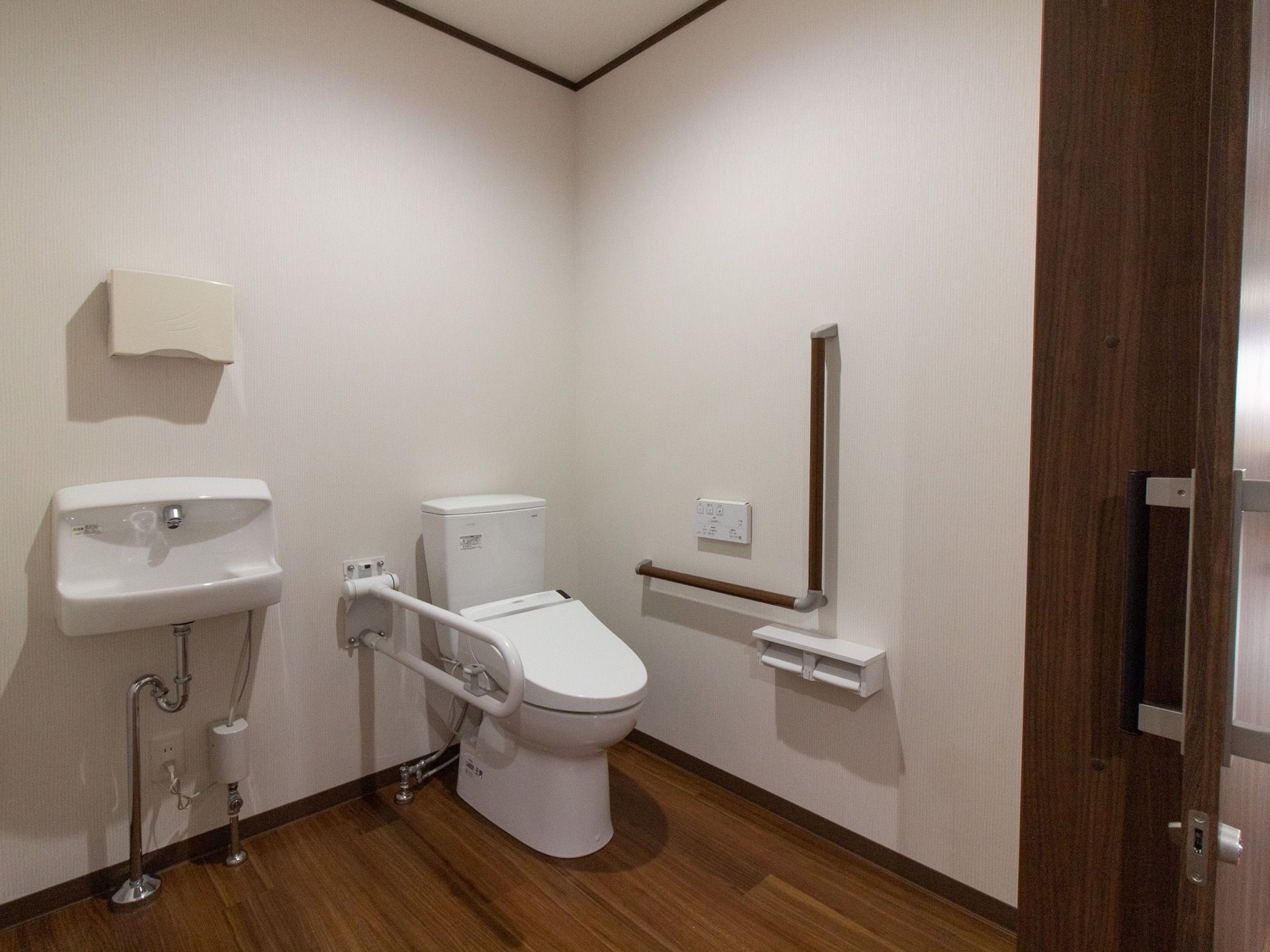 ゆとりあるスペースのトイレになっている。温水洗浄便座が採用されており、壁に操作ボタンが設置されている。