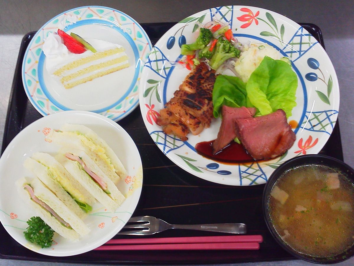 花の絵や明るい色で模様の描かれたお皿に肉料理やケーキが盛り付けられている