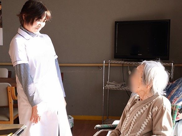 共有スペースにはテレビが設置されている。入居者の話をやさしく微笑みながら聞いているスタッフ。