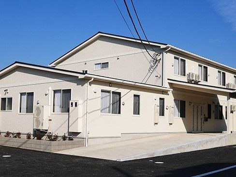 エントランスへ幅の広いスロープが設けられている、2階建ての施設外観
