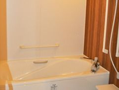 浴室を囲んでいる壁は、向きによって明るい白地や高級感のある落ち着いた茶色地のものがある。また壁には、掴まり用の棒が取り付けられている。