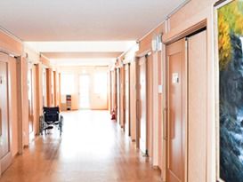 床や壁の色は茶色でナチュラルな雰囲気である。居室ドアは引き戸式になっていて、開け閉めしやすい。通路奥には消火器が設置されている。