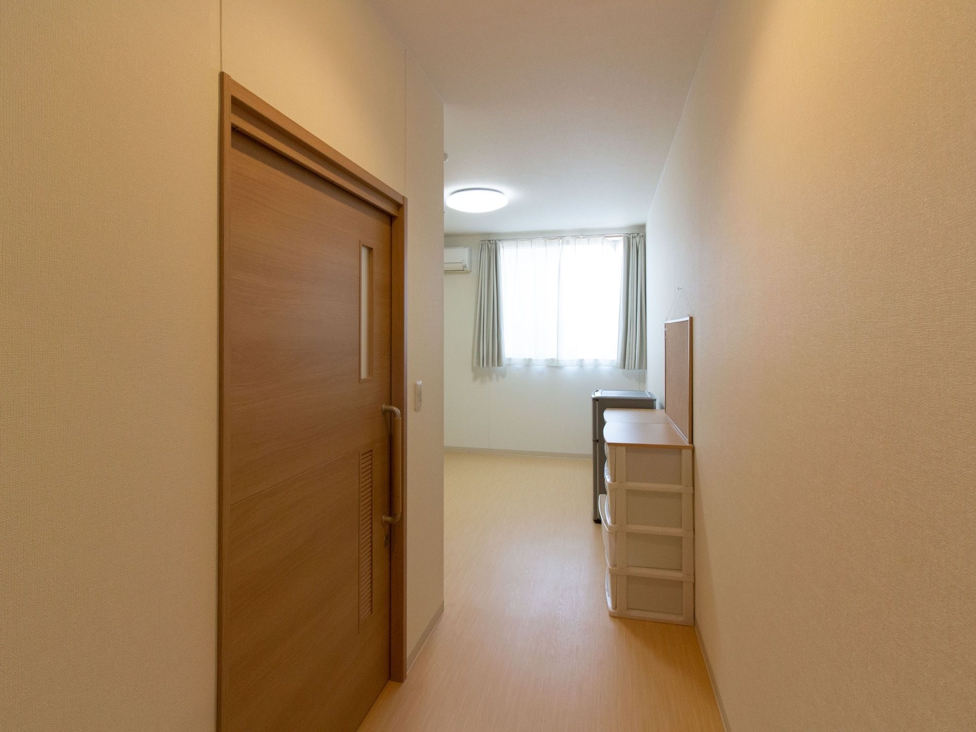 居室に入ると左手にトイレへの引き戸がある。正面は居住スペースへ繋がっており、チェストなどが置かれている。
