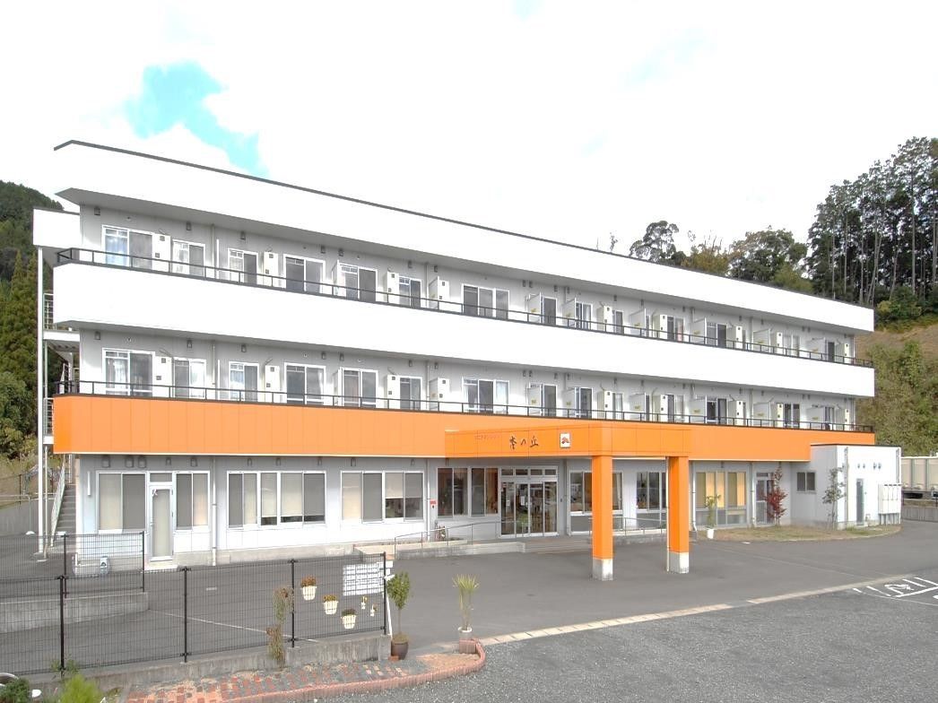 白色の壁にオレンジ色のタイルが目を引く綺麗な三階建ての建物。雨よけが付いているため、天候にかかわらずゆっくりと外出の準備ができる。
