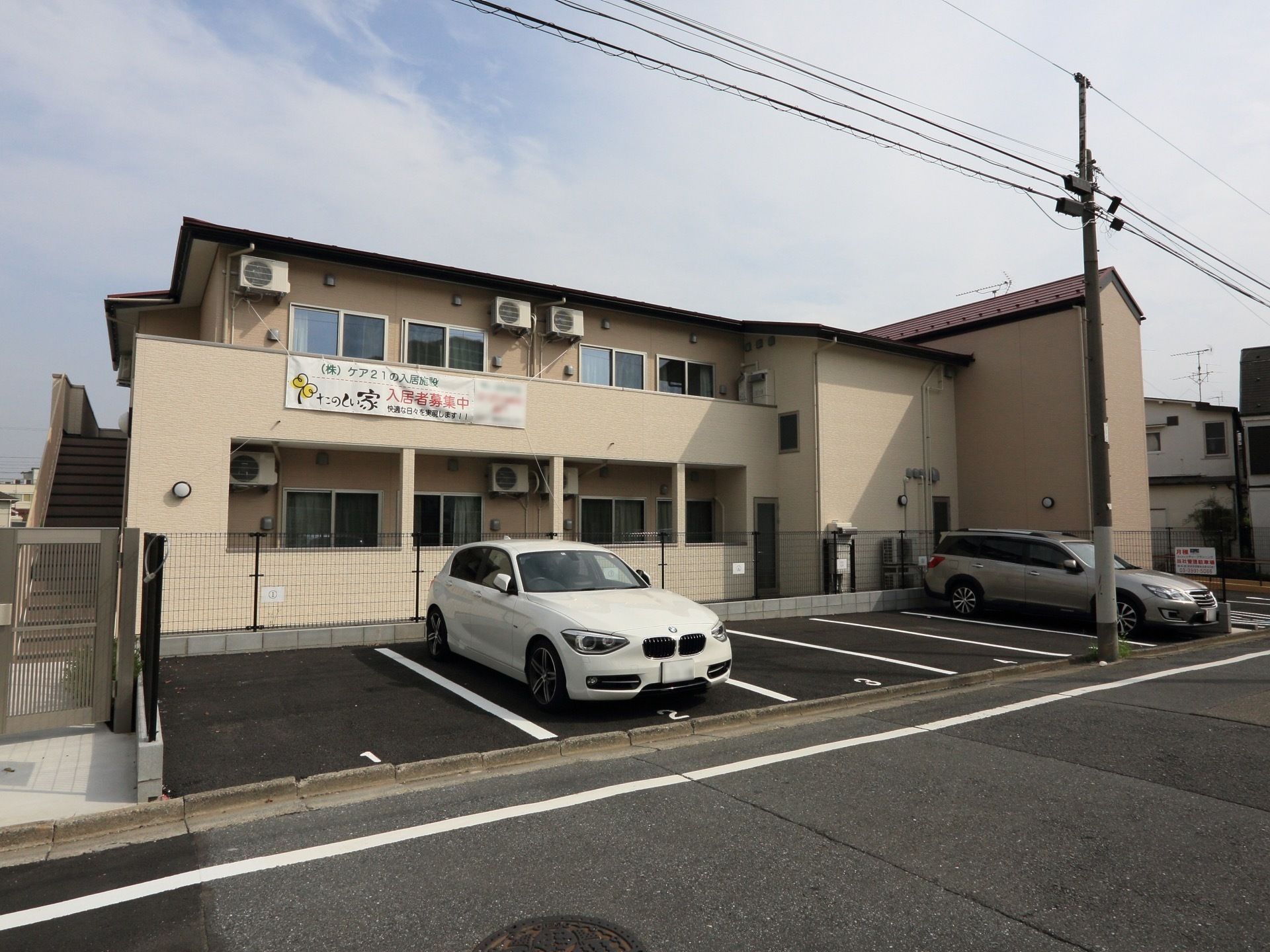 ２階建てで外階段とベランダのついた施設である。道路に面して駐車場が６台分ある。出入口には門を設置している。