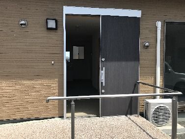 戸建てのような雰囲気の、スライド式ドアの居室玄関とスロープ