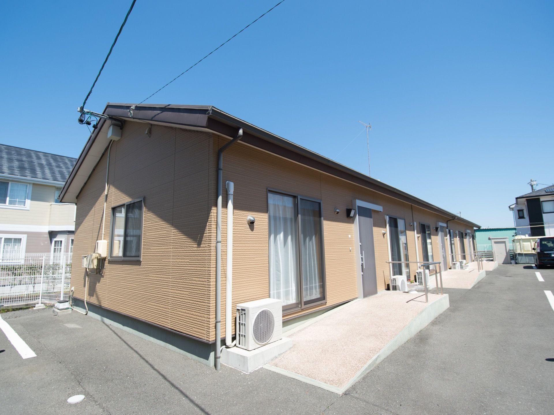 ブラウンの外壁で平屋造りである。一戸建てのような見た目である。それぞれの入り口前はスロープとなっている。