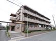 集合住宅の入口に階段がある。その左側には車両用のスロープがあり駐車場が奥にある。3階建ての1階部分が施設となる。
