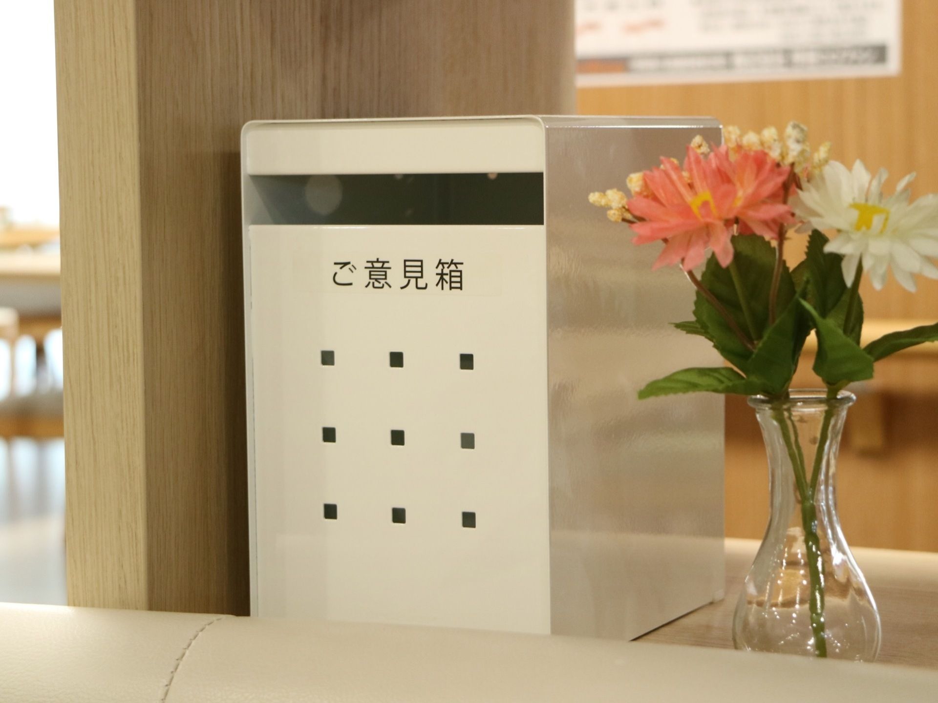 花が活けられた花瓶の横に、白い郵便受けのようなご意見箱が設置されている。施設では、入居者様の意見を取り入れてサービスの向上に努めている。
