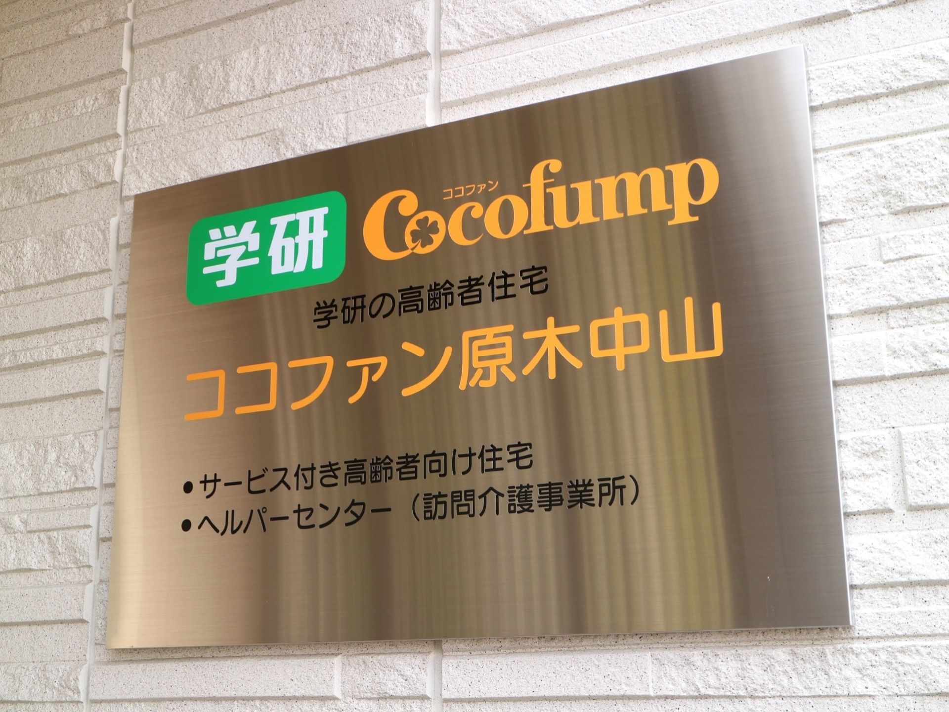 エントランスの壁には、メタリックの目立つ板に施設名が明記された銘板が取り付けられている。見やすいようにカラフルな色使いになっている。