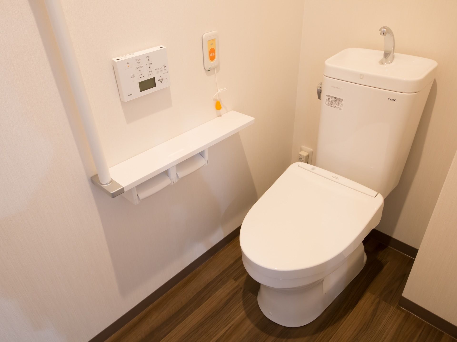 トイレの壁には手すりや呼び出しボタンを備えつけている。温水洗浄便座がついているため、温水で汚れを流すことができる。