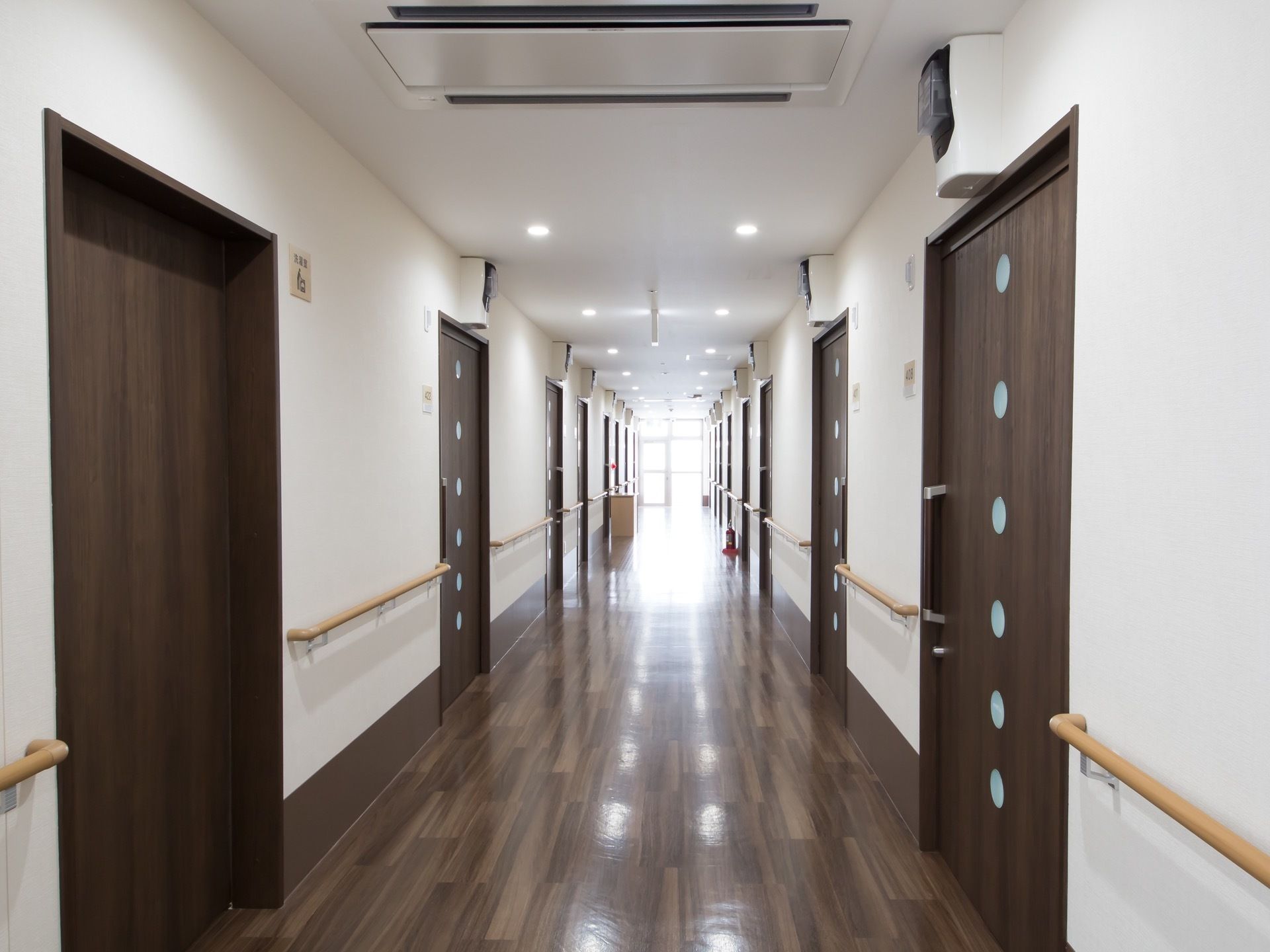 濃いブラウンの扉が並んだ通路は幅が広く、明るくなっている。手すりが設置されているため歩行が楽に行える。