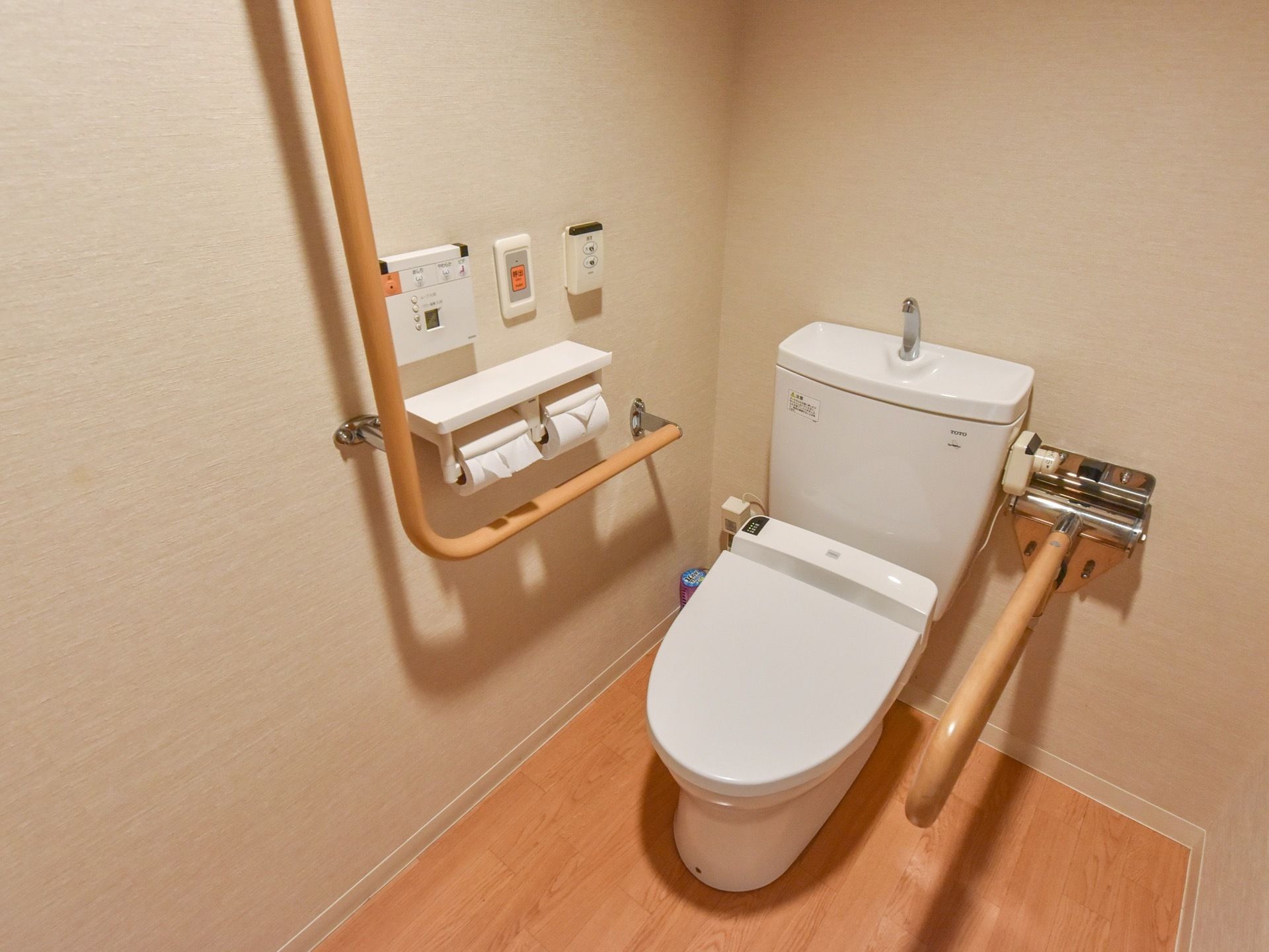 トイレはフローリング張りでナチュラルな雰囲気である。Ｌ字型の手すりと可動式の手すりが設置されている。
