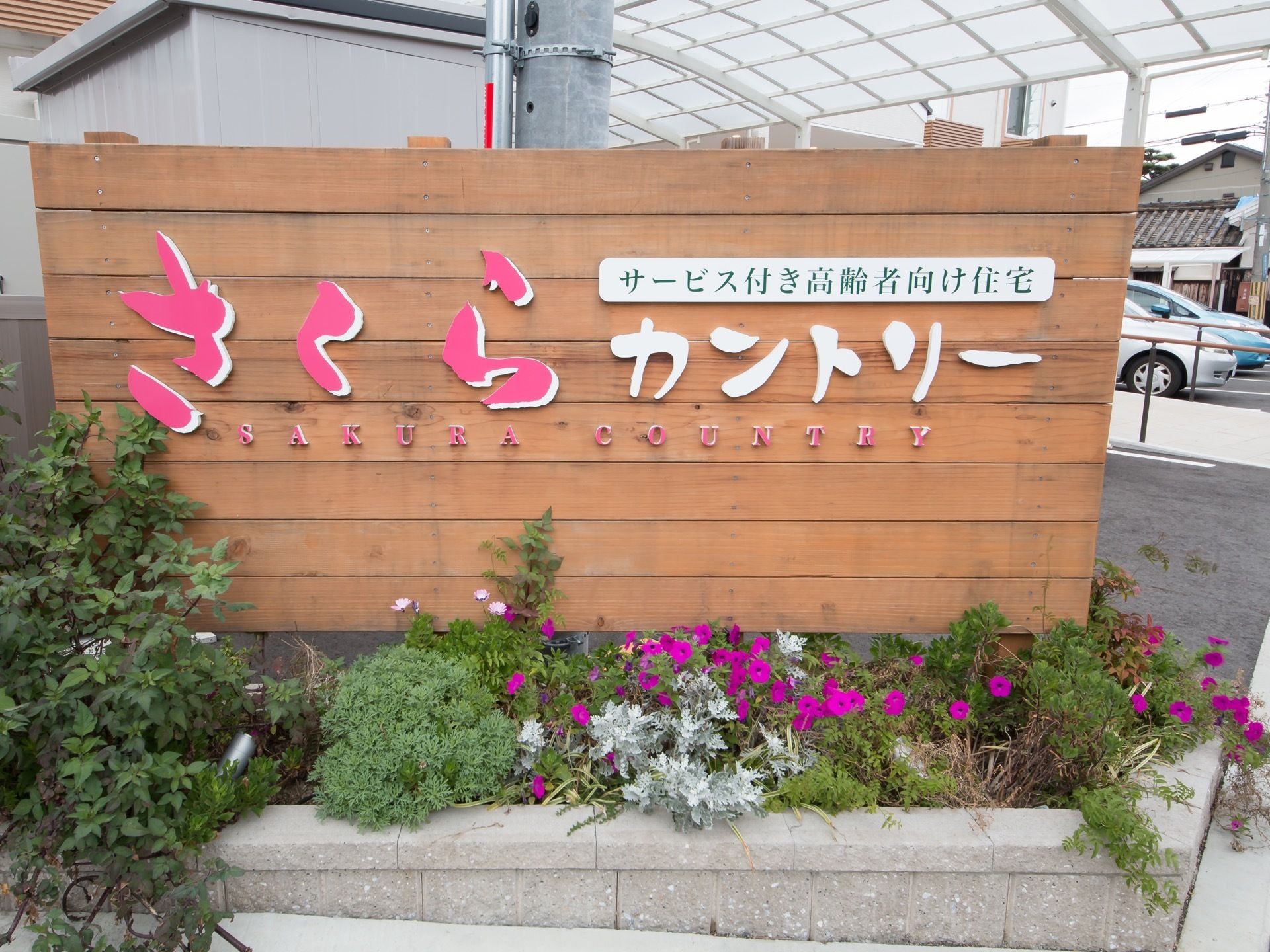 施設外には大きい看板を置いている。看板の下には草花がたくさん植えられている。ナチュラルな雰囲気となっている。