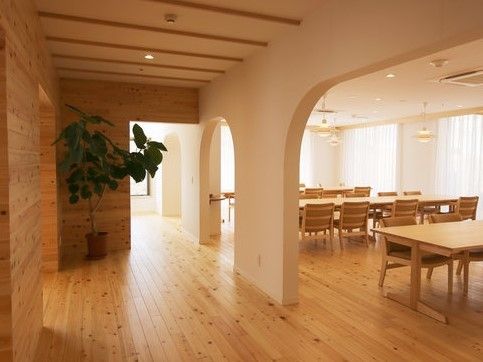 奥にテーブル席が並んでいる。流線形の仕切りは、入居者様が穏やかな気持ちになれる空間を目指して作られた。
