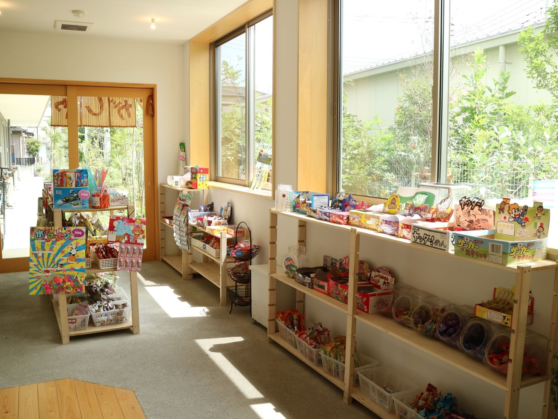 入口の扉はガラス張りで、上部には店名を書いたのれんを掛けている。内部には木製の棚を配置し、たくさんの駄菓子を並べている。