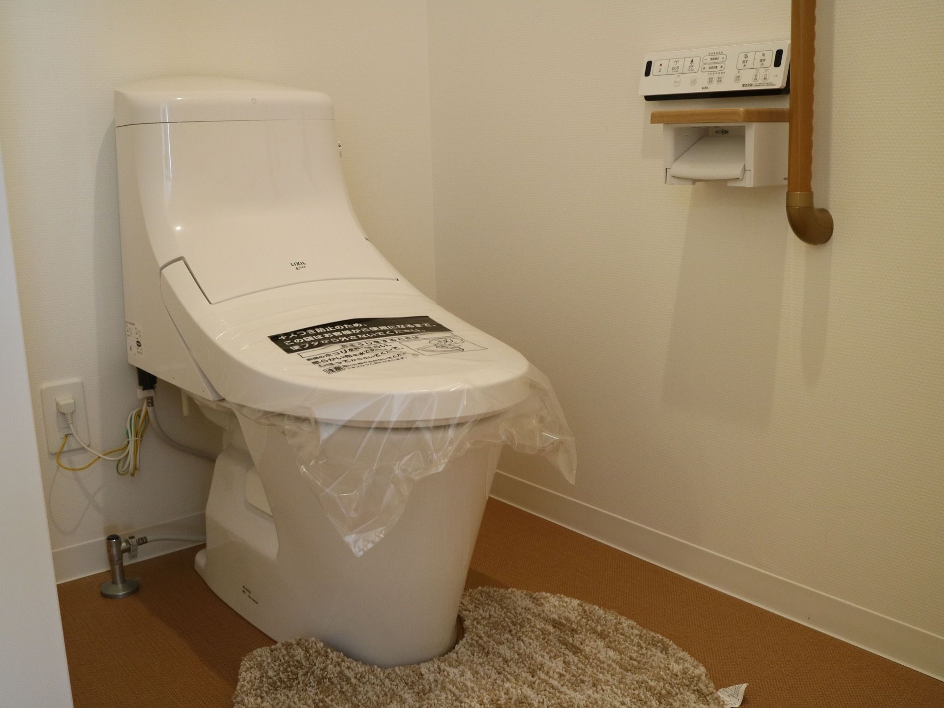 洋式便器には温水洗浄便座を完備している。床はフラットなフローリングで、壁には木製の手すりを取りつけている。