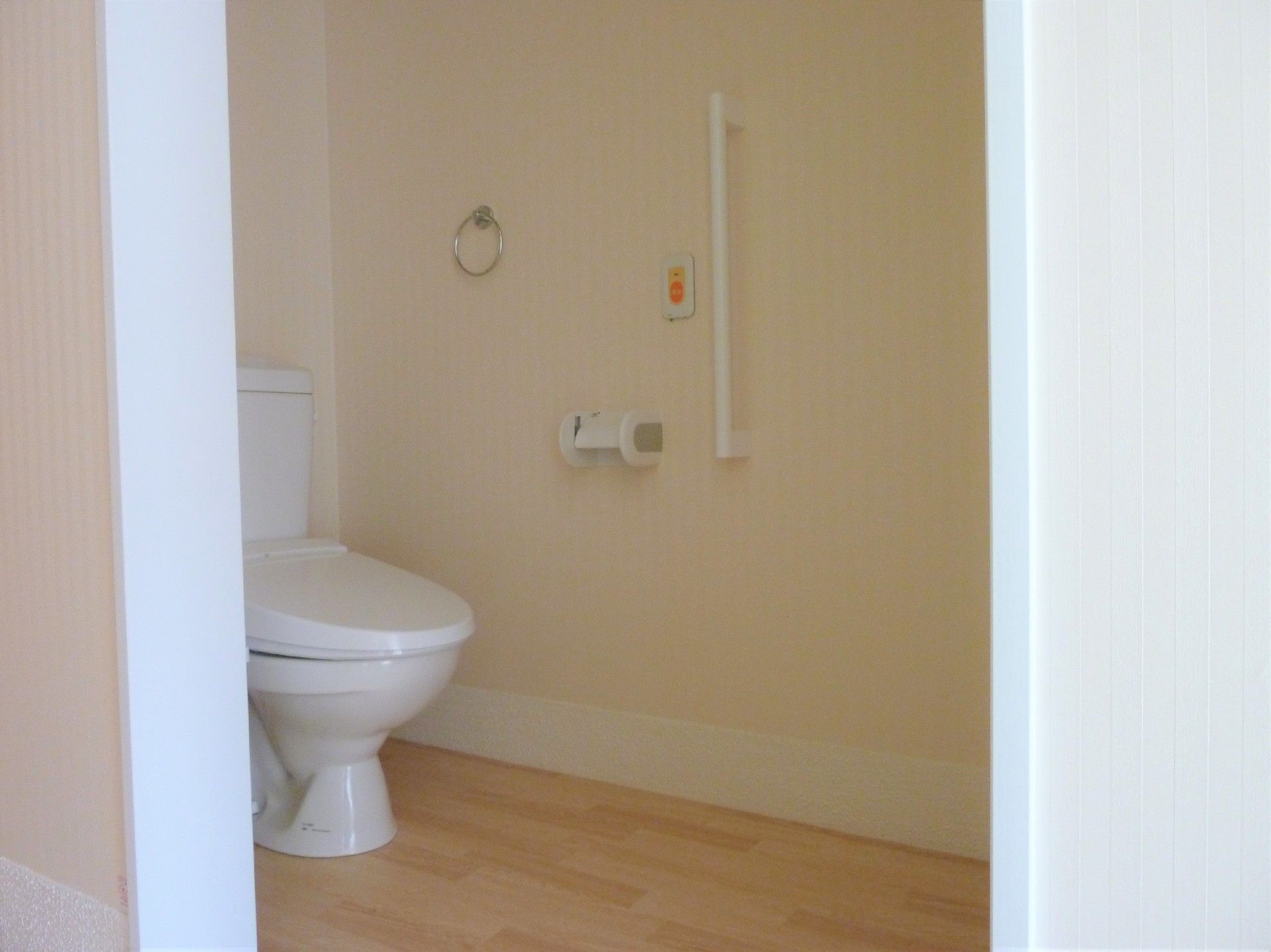 トイレが正面にある。その奥の壁にはトイレットペーパーホルダーやタオル掛けがあり、一般家庭と同じように使用することができる。